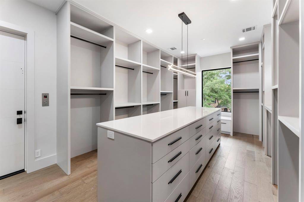The Primary closet has an island with drawers on one side and doors on the other side with lots of storage.  Countertop on the right is perfect for a watch winder.  The door on the left is access to the elevator that will deliver you straight to the garage for a quick exit.