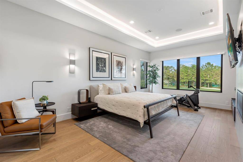 The spacious primary bedroom features cove lighting, and a comfortable seating/exercise area. Large windows offer plenty of natural light and a scenic view of the 11th fairway of the TPC golf course. A wall-mounted TV above a 42" raised fireplace with tiled surface.