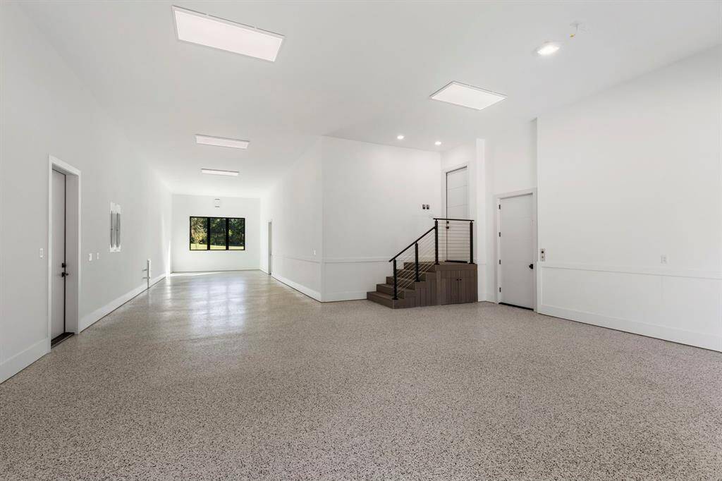 The 4-car garage has a single bay and a triple bay that is 65' long. The 13' high ceilings are prewired for car lifts. The elevator door is on the right.  The door at the back right leads to the pool/spa deck.  The door on the left leads to the whole home generator and pool equipment.