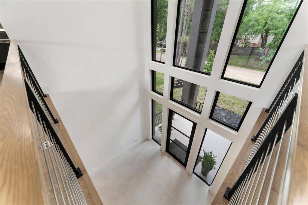 View from the second-story landing overlooking the front vestibule with a wall of windows filled with natural light.