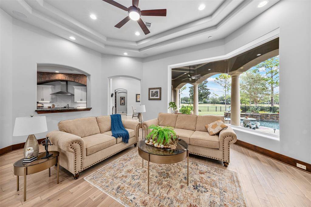 The living room features a breathtaking view of the private backyard pool and golf course, complemented by a modern fireplace that creates a classy ambiance, enhanced by abundant natural light.