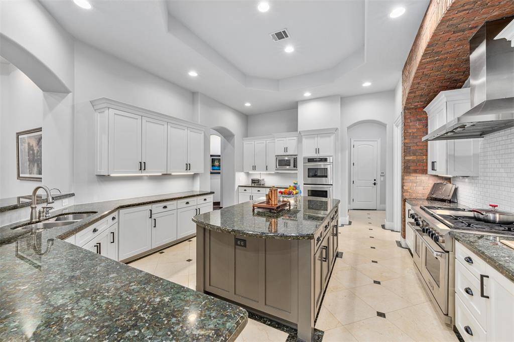 The kitchen is open and spacious, featuring ample cabinetry for storage and a beautifully convenient island table at the center, perfect for meal preparation and casual dining.