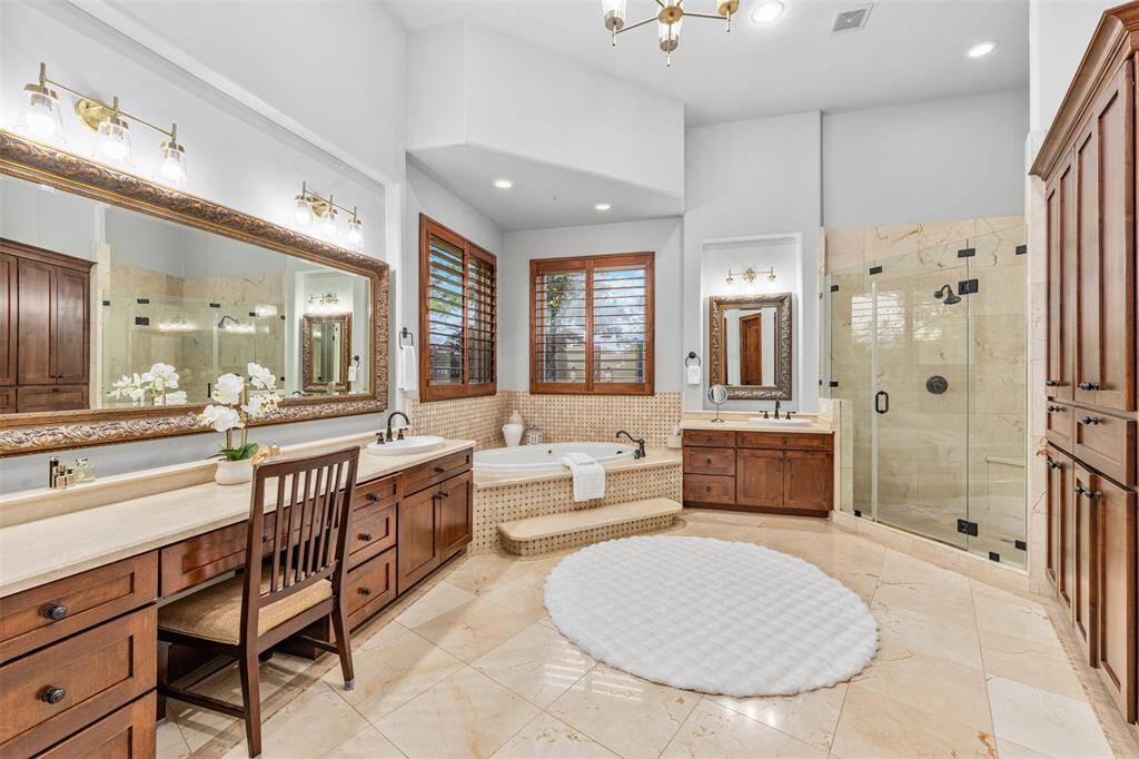 The primary bathroom features a double sink, a jetted spa/hot tub, and a dedicated makeup area, creating a luxurious retreat for relaxation and pampering.