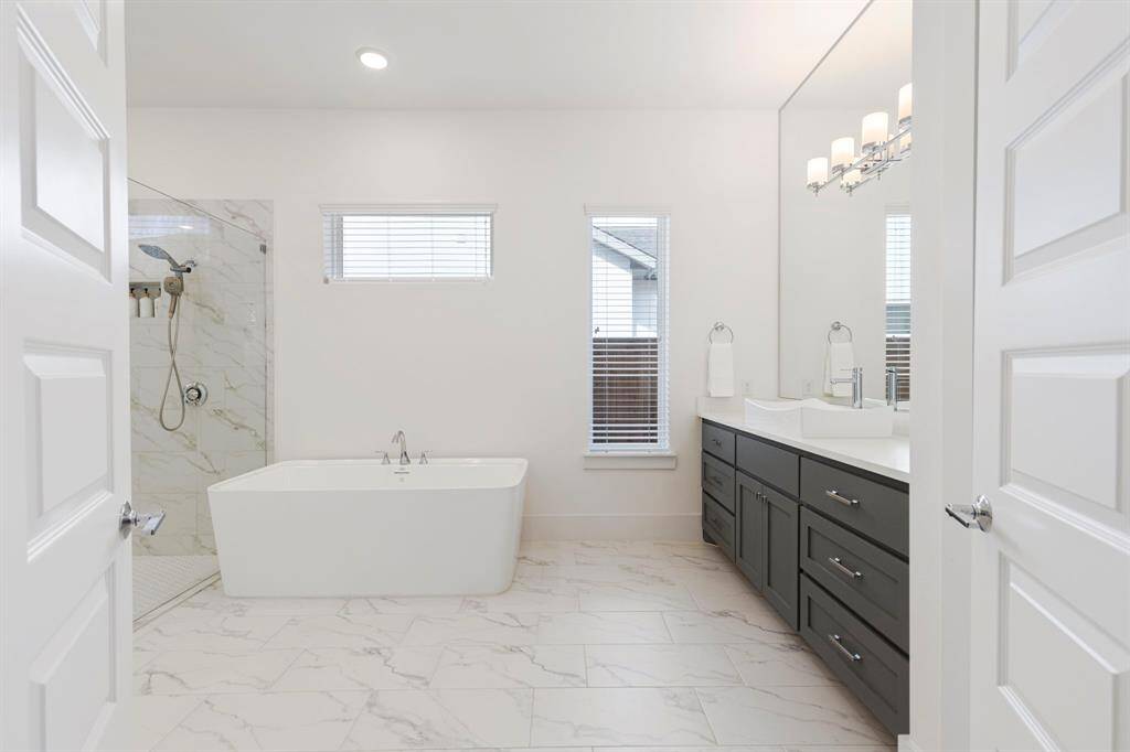 Entering through two double doors into the massive primary bathroom, with soaking tub, his and her vanities and closets.