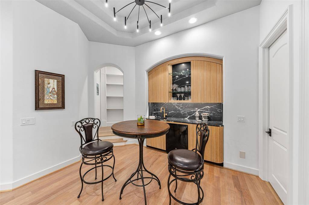 The bar area creates a relaxed atmosphere, perfect for unwinding and entertaining, enhancing the home's comfortable and easygoing vibe. To the left is a bookcase hallway to filled with books and decor.