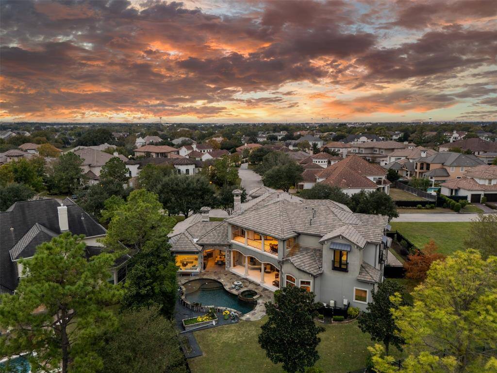 This luxurious two-story home in a gated golf course community featuring a private pool, outdoor kitchen, and a spacious balcony with a golf course views.