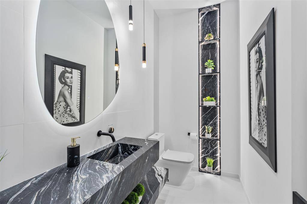An elegant powder room featuring a striking black marble countertop that adds a touch of sophistication. This high-class half-bathroom is perfect for guests, blending style and comfort seamlessly.