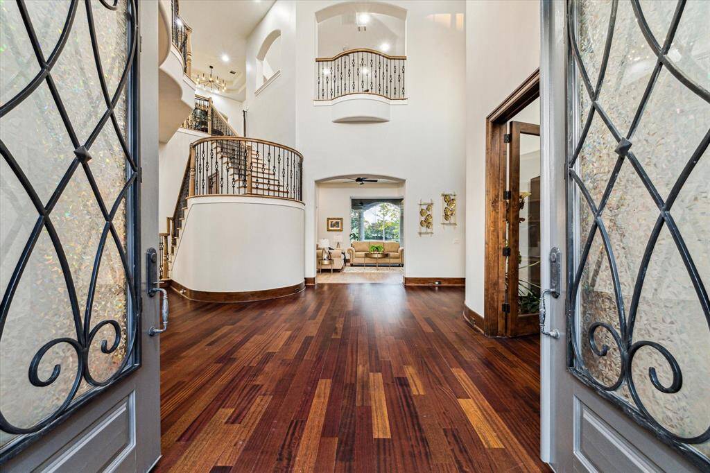 This two-story luxury home features stunning high ceiling with interior lighting that beautifully illuminates the space, providing a seamless view of the inviting pool and backyard straight ahead, with an elegant office to the right for a perfect balance of work and relaxation.