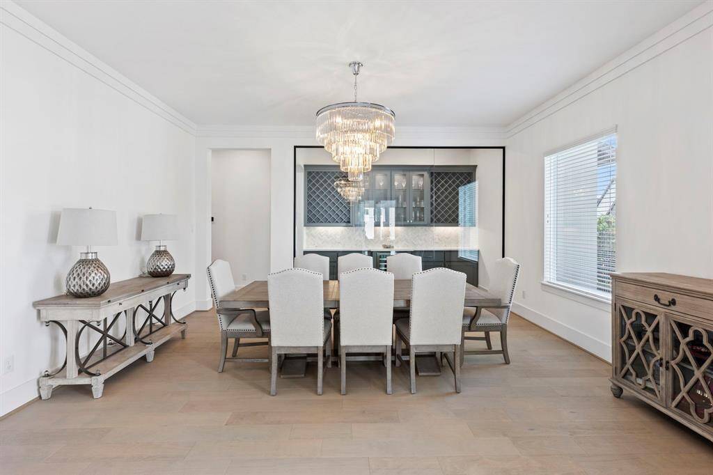 Beautiful formal dining room with upgraded chandelier and glass wine room feature wall.