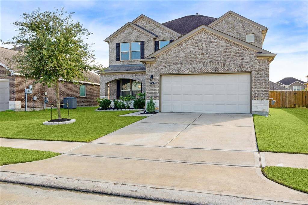 This is a modern two-story brick home with a neatly landscaped front yard, featuring a two-car garage and a spacious driveway.