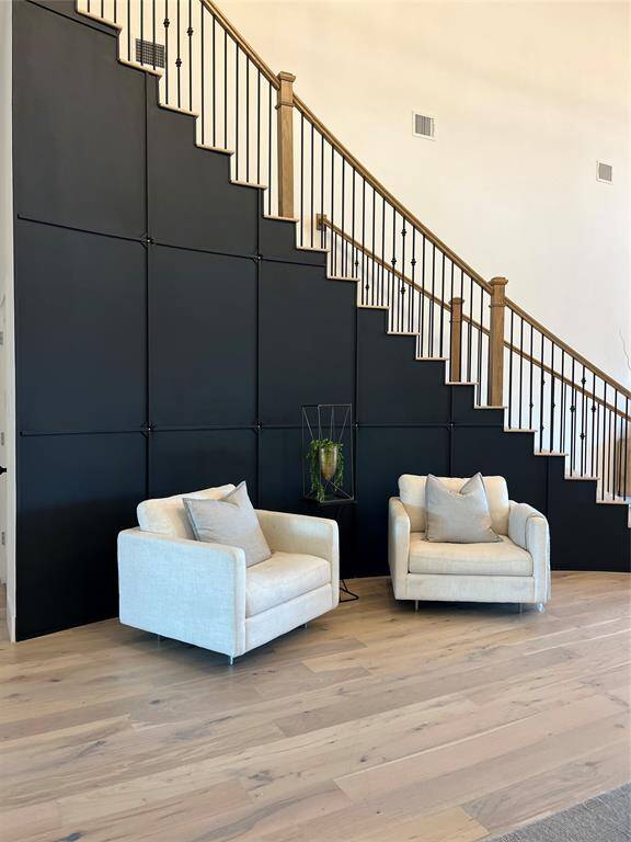 Striking black accent wall under a staircase with wooden railings. Perfect for a cozy sitting area.