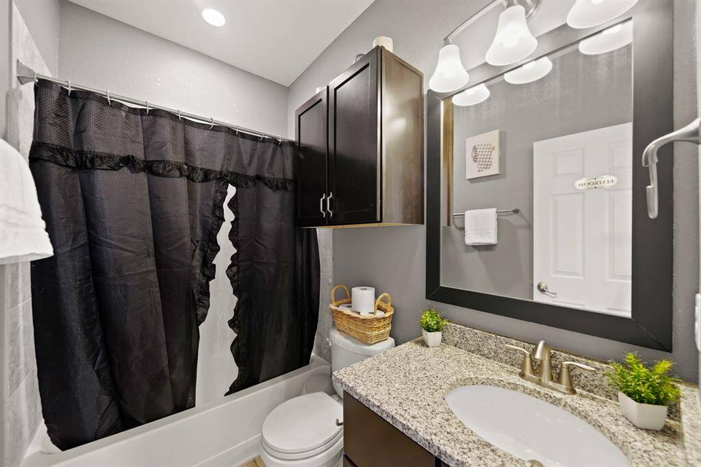 Stylish bathroom featuring granite countertops, dark cabinetry, and modern fixtures, with a shower-tub combo for convenience.FULL BATH (rare) first floor. Extra storage space above the toilet.