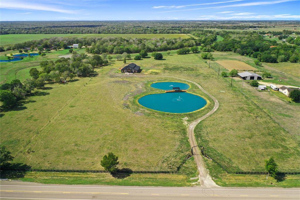Expansive rural property featuring a large, scenic pond with two fountains and a charming house surrounded by open fields. Ideal for those seeking tranquility and natural beauty.