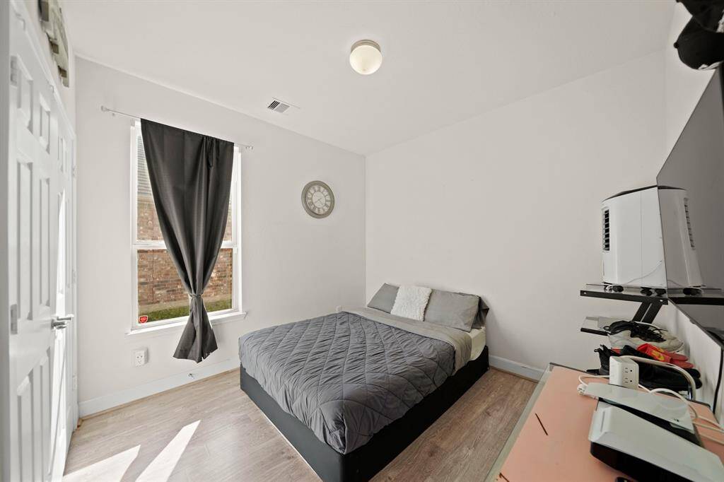 Guest bedroom on the first floor. Cozy bedroom with ample natural light, wood-style flooring, and a minimalist design for a comfortable retreat.