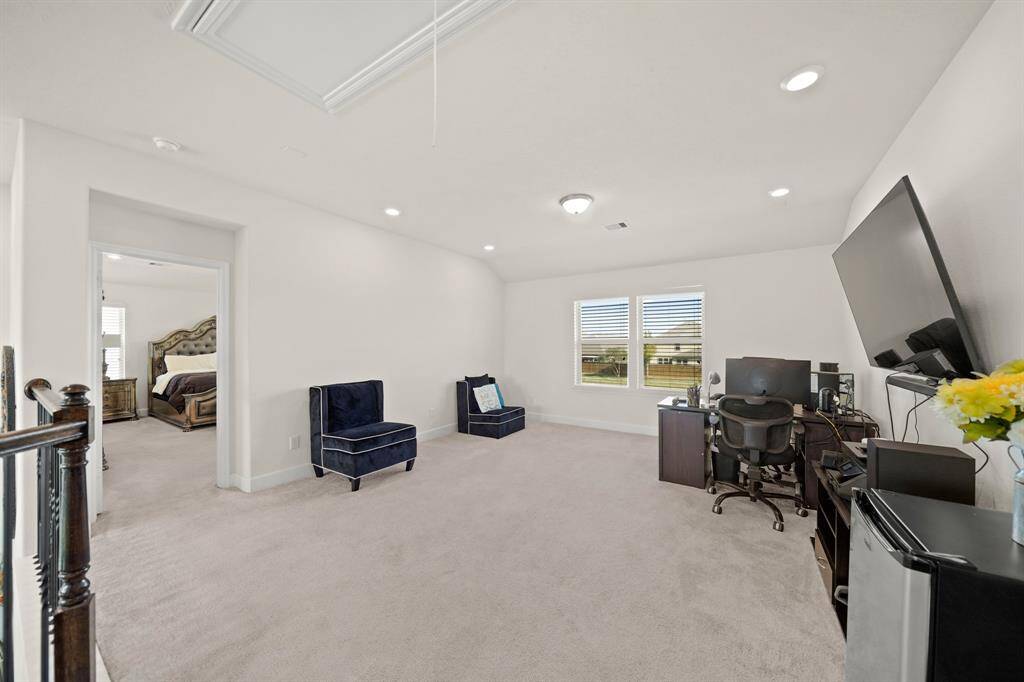 This spacious game room, with its natural light and plush carpeting, is a versatile space ideal for work, play, or relaxation. The possibilities are endless with this space.