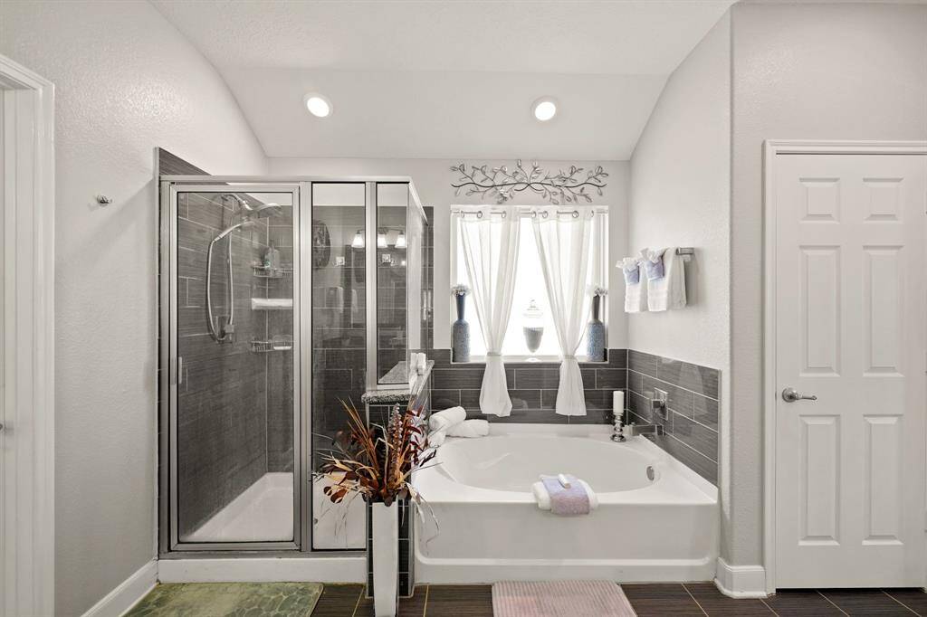 Located upstairs... A luxurious primary bathroom featuring a relaxing soaking tub, a glass-enclosed walk-in shower, and stylish tilework offers a spa-like retreat. The linen closet is also in the ensuite, allowing extra space for storage.