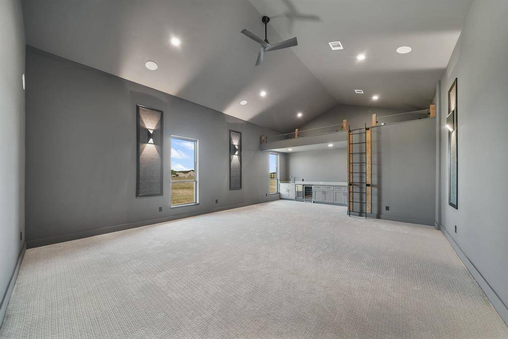possibilities are endless in this spacious modern room with high ceilings, ample natural light, and a built-in wet bar. Features a sleek ladder leading to an upper storage or play area, ideal for entertainment or relaxation.