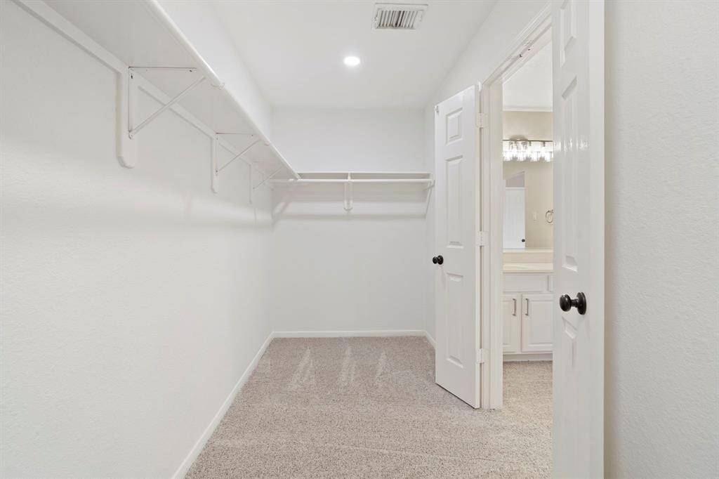 The primary walk-in closet features plush new carpet, recessed lighting, and plenty of storage space.