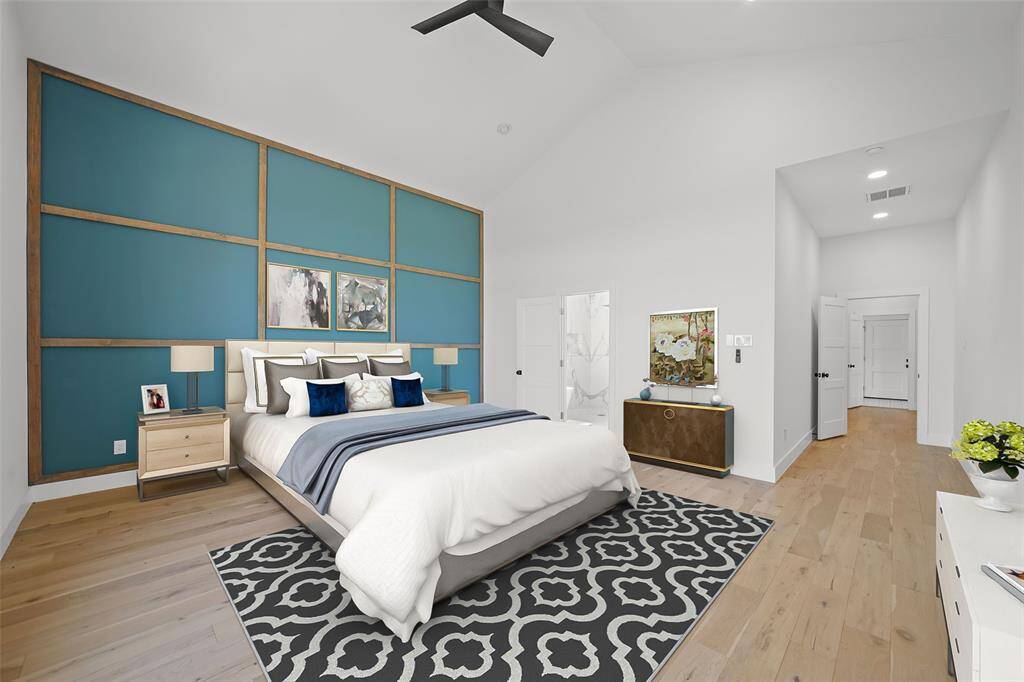 Primary bedroom features a vaulted ceiling and a stylish accent wall with geometric paneling. It includes hardwood floors, stunning touches, and ample natural light.Virtual staged setting