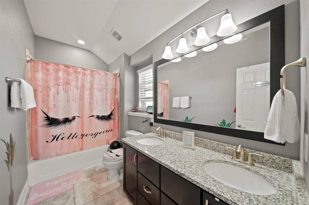 The second full bathroom is upstairs. It is bright and features dual sinks with granite countertops, plenty of storage under the countertops, a large mirror, and a stylish shower-tub combo, perfect for shared or guest use. There is also a Linen closet in the hallway for extra storage.