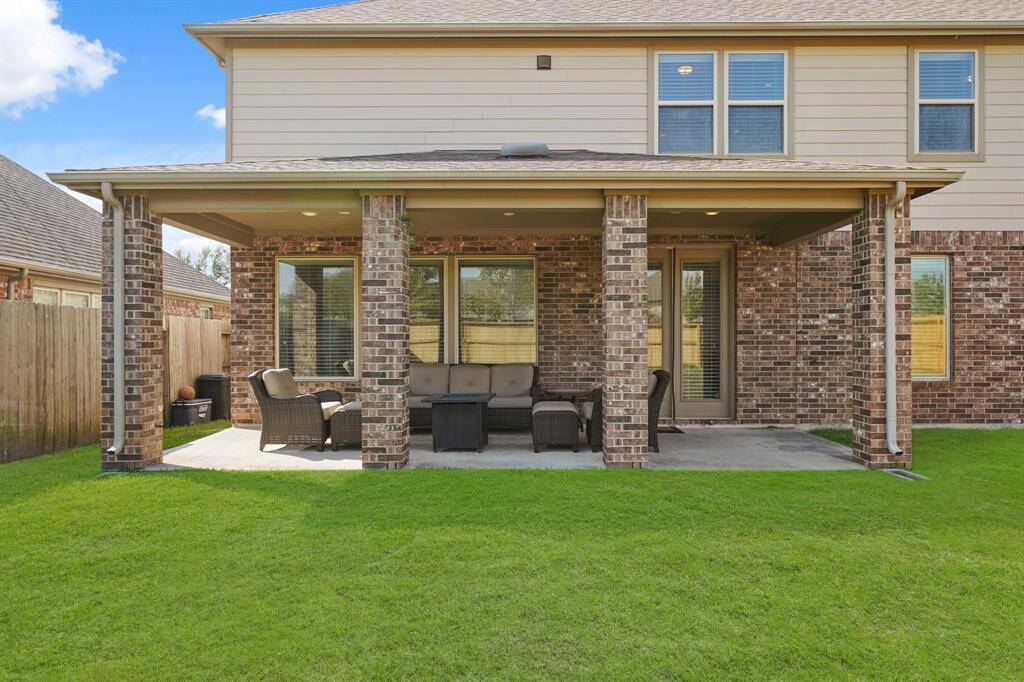 Beautiful brick-accented covered patio overlooking the spacious backyard, providing a perfect space for outdoor relaxation and entertaining.