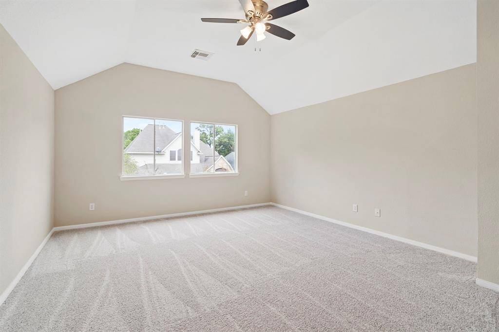 The game room features plush new carpet, high ceilings, large windows, and a ceiling fan.