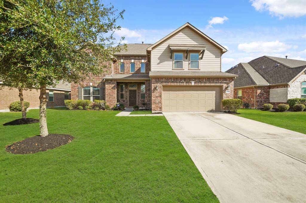 Stunning two-story home with a modern brick and stone facade, with a spacious driveway leading to a two-car garage.