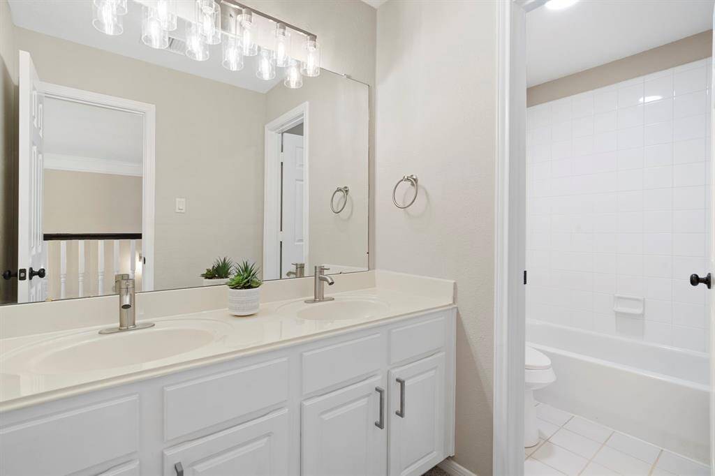 Secondary bathroom features atub/shower combo and longvanity with dual sinks.