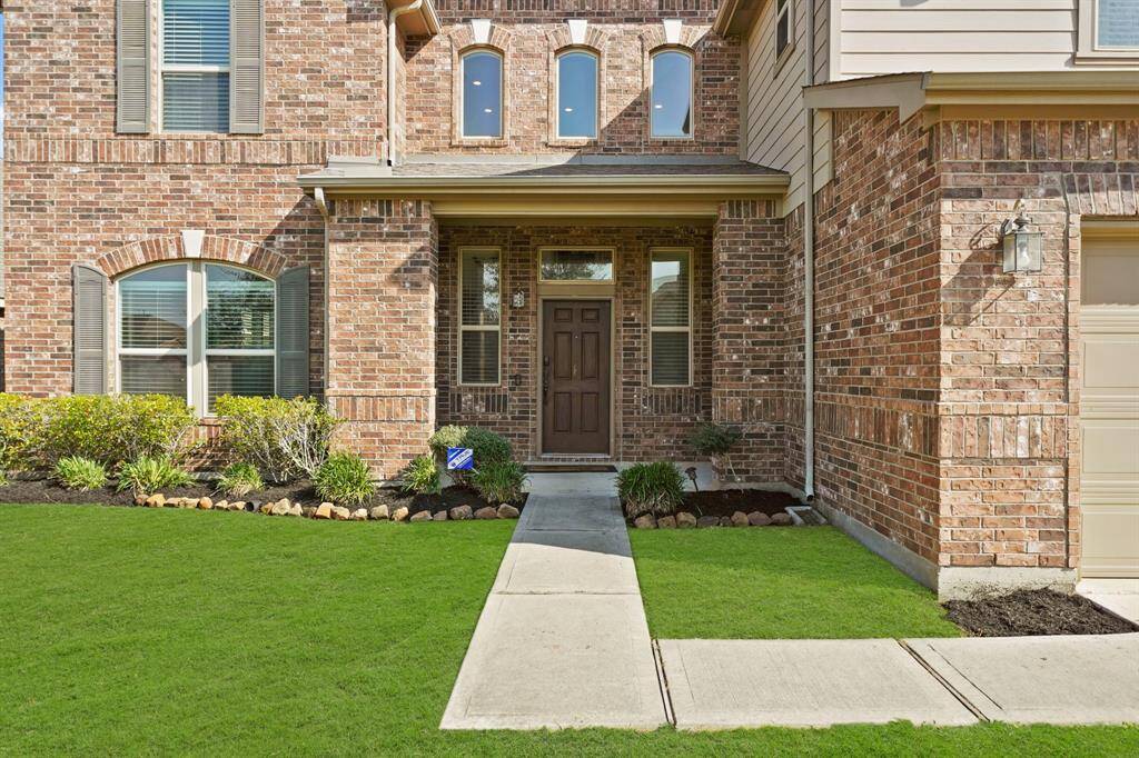 Charming brick exterior with arched windows, a welcoming front door, and a clean walkway.