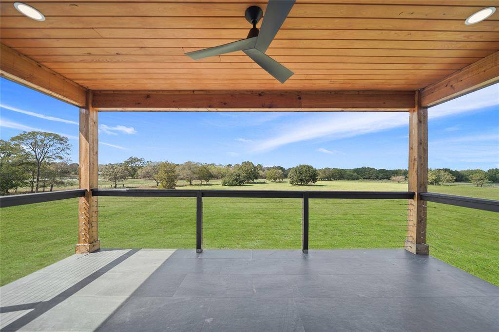 Upstairs balcony overlooking the expansive views of lush green fields and trees, perfect for relaxing.