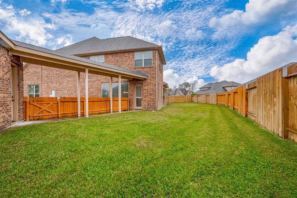 Spacious , surrounded by a wooden fence. The brick house has a covered patio area, perfect for outdoor activities.