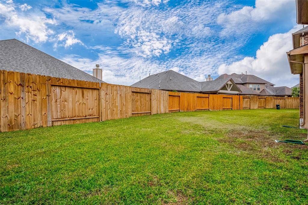 Spacious backyard, enclosed by a wooden fence, offering privacy and ample space for outdoor activities.
