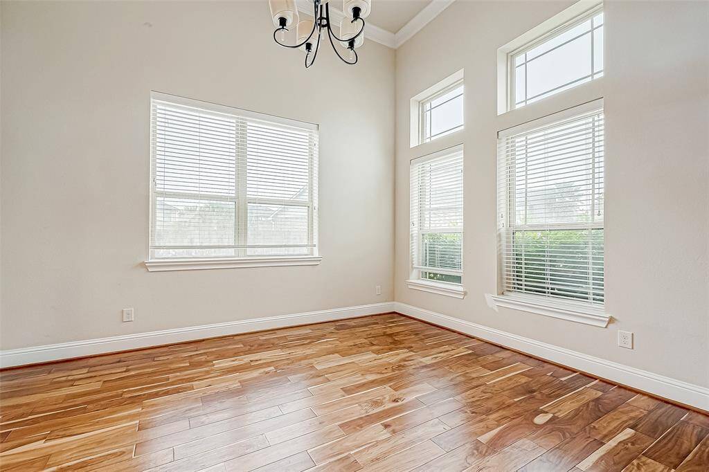 Bright room with large windows, hardwood floors, and a modern chandelier. Ideal for a dining or living space.