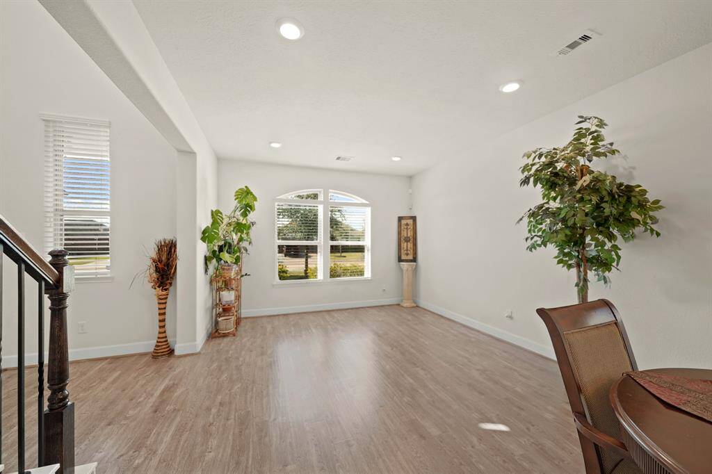 A view of the formal living area, with natural light, wood-styled flooring, and an open layout perfect for gatherings and entertaining.