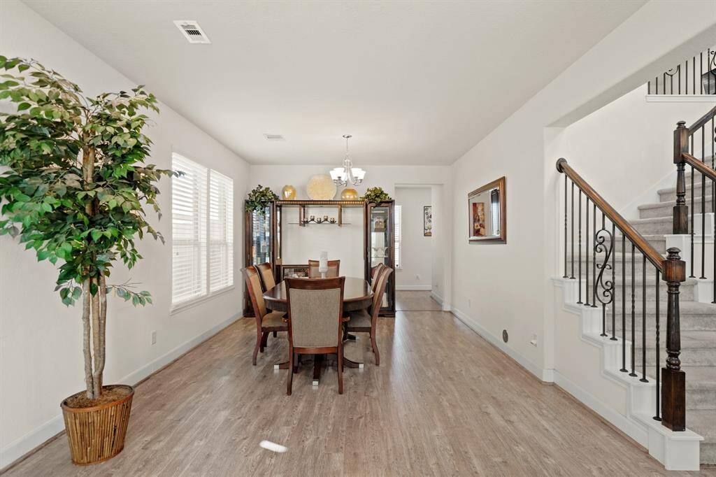 A view of the formal dining area, natural light, wood-style flooring, and an open layout is perfect for gatherings and entertaining, with the entranceway into the kitchen.