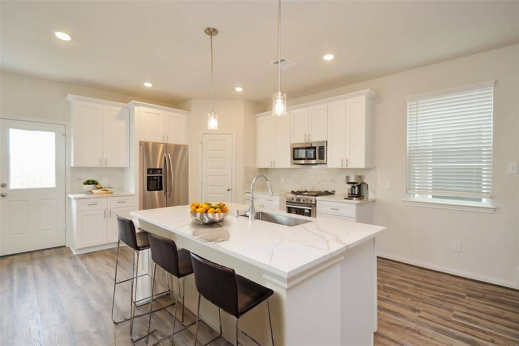 Notice the sleek white cabinetry offering ample storage, complemented by modern stainless steel appliances.