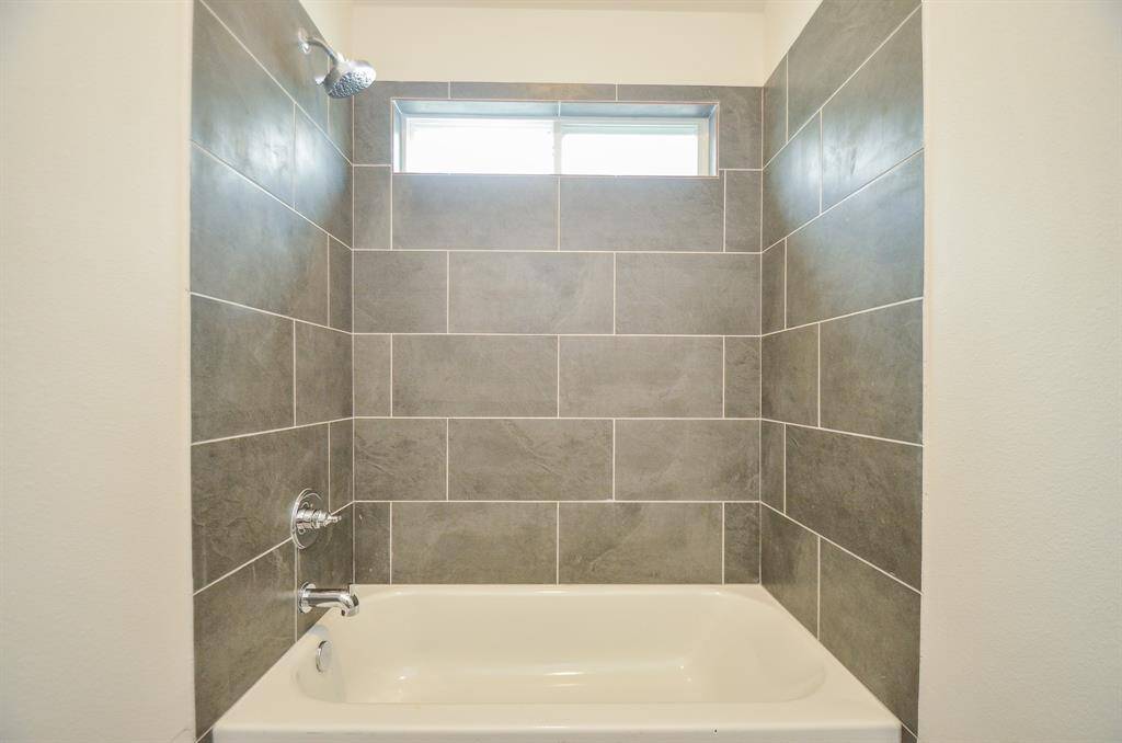 The shower/tub combination features a stylish tiling that is easy to clean.