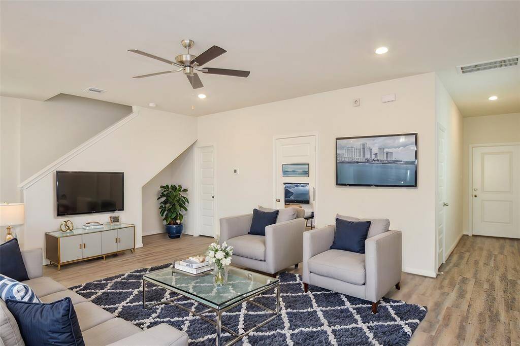 Natural light floods the room, highlighting the neutral walls and the flow towards the staircase.