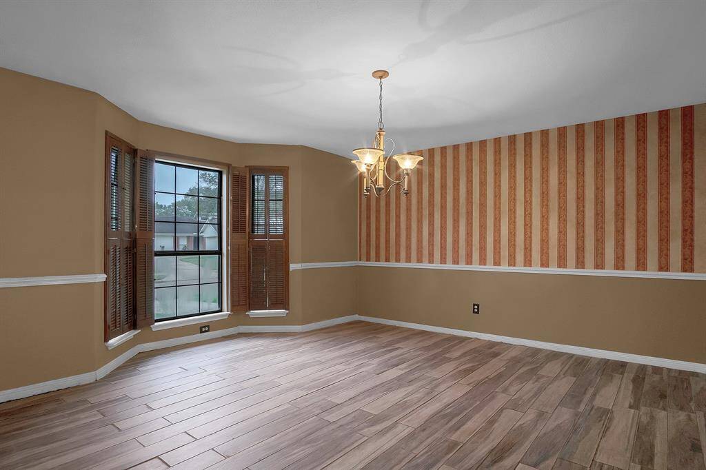 The formal dining room is spacious and ideal for entertaining, with "wood-look" tile flooring that adds warmth and elegance. A classic chair rail and a striking chandelier enhance the room's refined atmosphere, while large windows fill the space with natural light, creating a bright and inviting setting for any occasion.