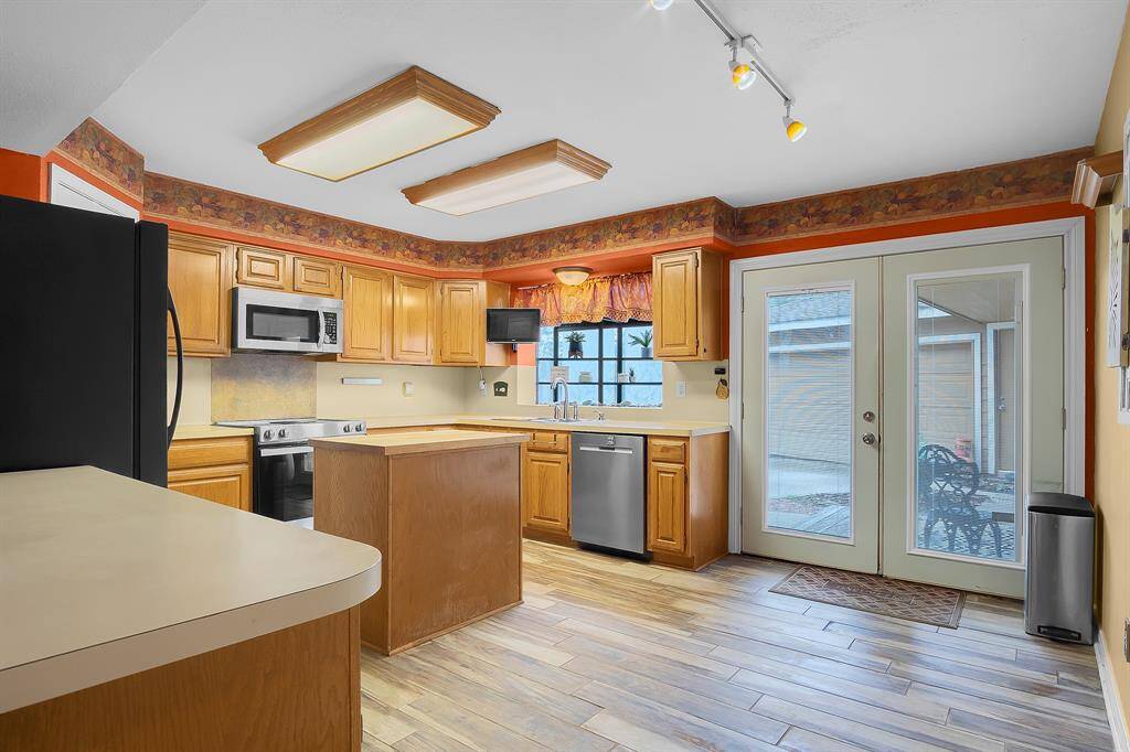 The kitchen boasts updated stainless steel appliances, a walk-in pantry, and original hardwood cabinets, offering plenty of storage and functionality. An island makes entertaining a breeze and the peninsula connects the space to the formal dining room, while a bay window is perfect for a herb garden.