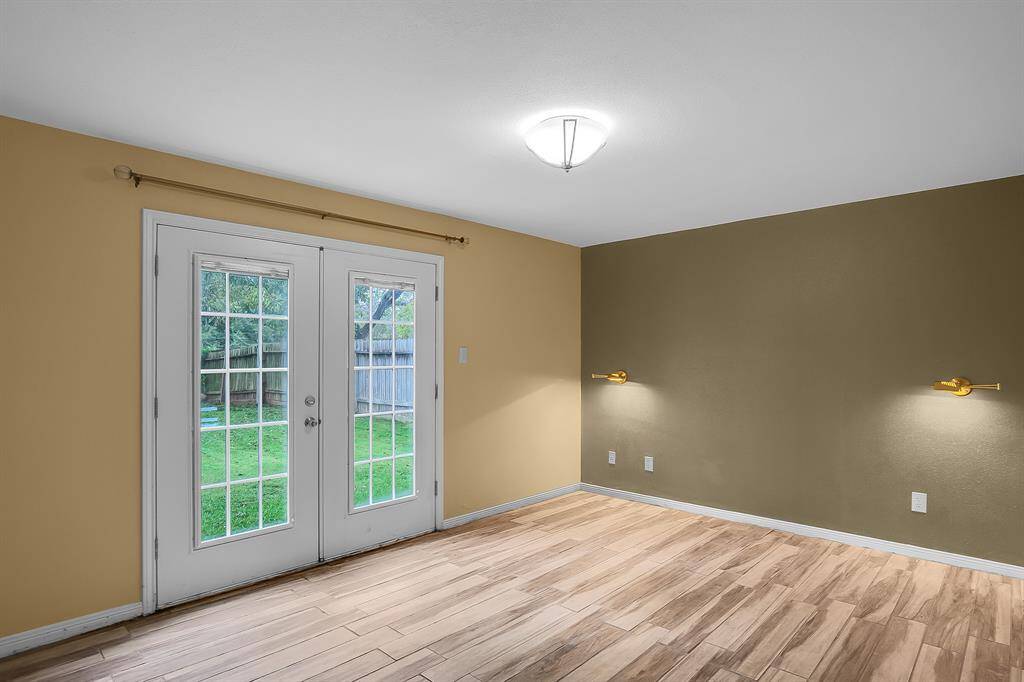 The downstairs primary bedroom is a serene retreat, showcasing beautiful "wood-look" tile flooring that seamlessly ties the space together. French doors open to the backyard, offering a peaceful view and easy access to outdoor living, while four generous closets—including two walk-ins—ensure ample storage. The ensuite bathroom is a luxurious haven, featuring granite counters, a double vanity, and a dedicated vanity sitting area for added convenience and comfort.