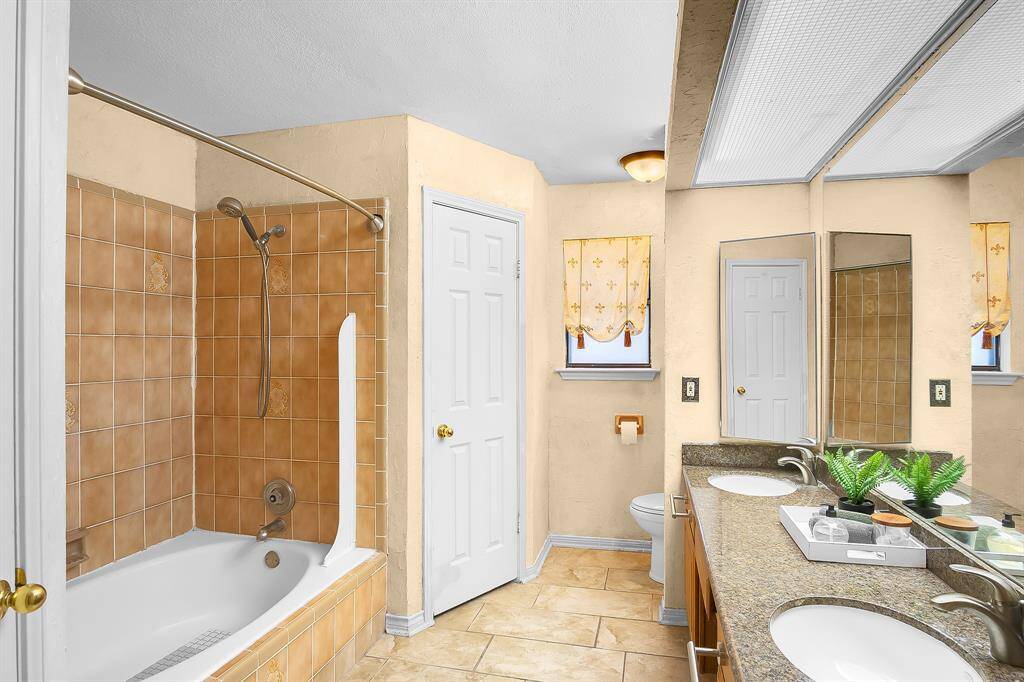 The primary bathroom is a spa-like sanctuary, with updated tile flooring that adds a modern touch. The sleek under-mount sinks and elegant granite counters create a sophisticated aesthetic, while the soaking tub/shower combo offers a relaxing retreat, perfect for unwinding after a long day. There are also 2 walk-in closets in the primary bathroom!!