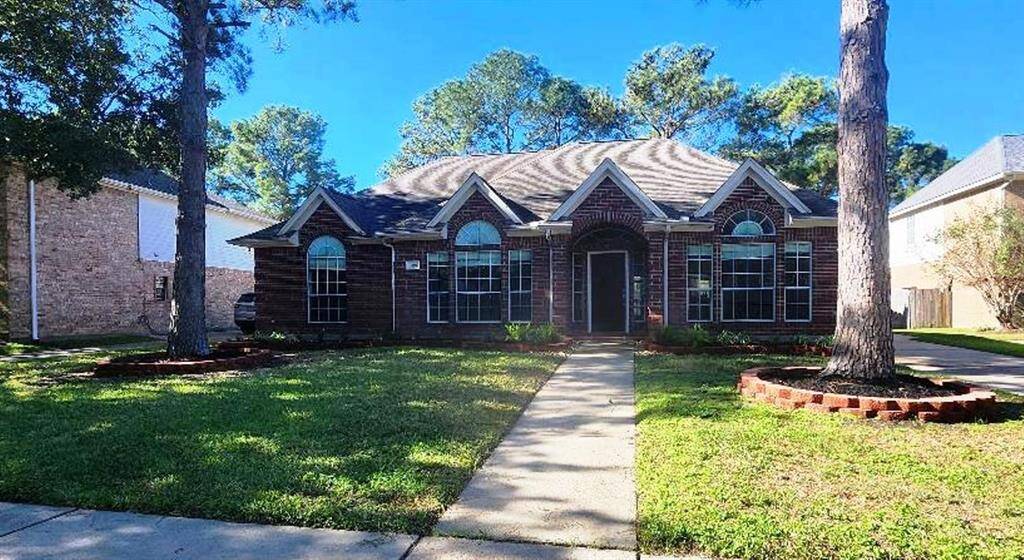 Charming single-story brick home with a welcoming front walkway. Features large arched windows, a well-maintained lawn, and mature trees providing shade. Ideal for a cozy family living.