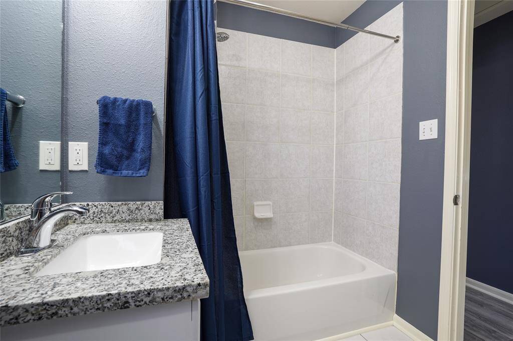 Unit B - Upstairs hallway bathroom has tile flooring, window with blinds, granite counter, and shower/tub combo.