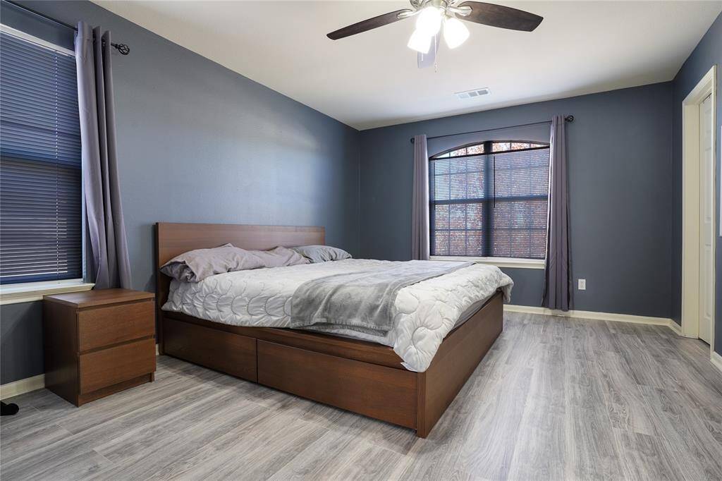 Unit B - Large primary bedroom. Located upstairs with laminate flooring, ceiling fan, and large windows with blinds.