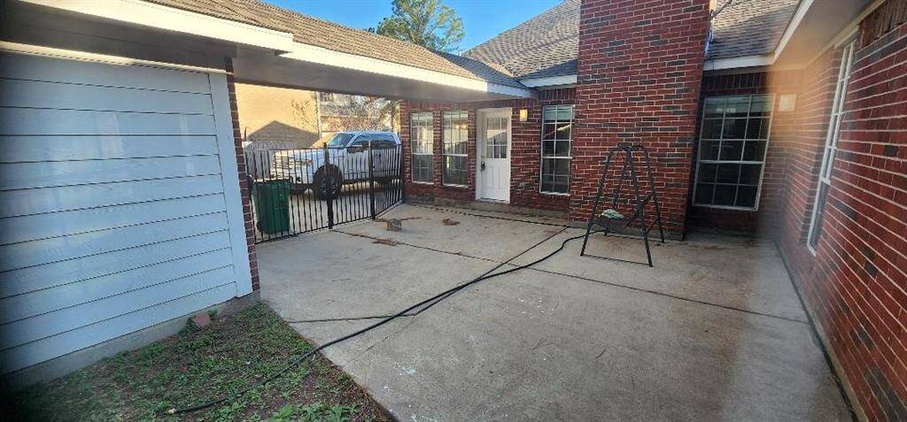 This photo shows a spacious backyard patio with brick walls and a concrete floor. It features a swing and has ample natural light, offering a private outdoor area for relaxation or entertaining.