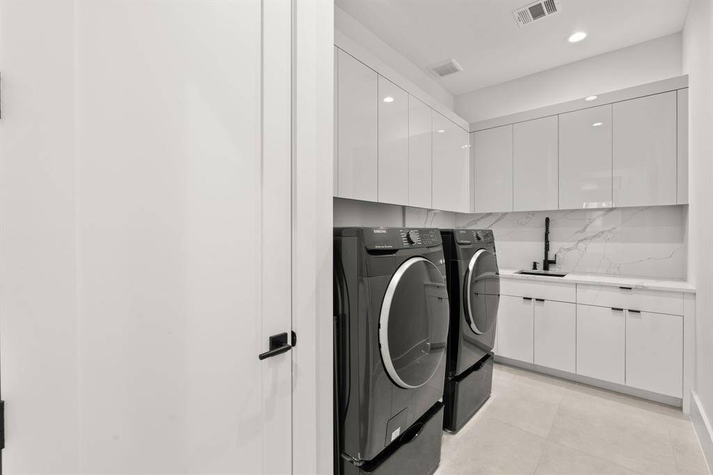 Even the utility room exudes luxury, with stunning tile flooring, a sleek countertop and backsplash, and seamless storage cabinets, making laundry day a breeze.