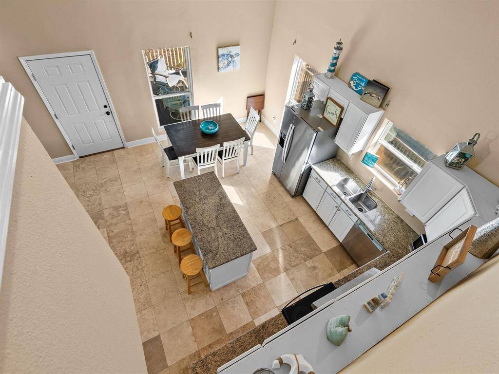 This open-concept floor plan features a spacious kitchen with modern stainless steel appliances, ample counter space, and a central island with seating. Adjacent is a cozy dining area with a table and chairs, well-lit by natural light from large windows. The layout is welcoming and functional, ideal for both daily living and entertaining.