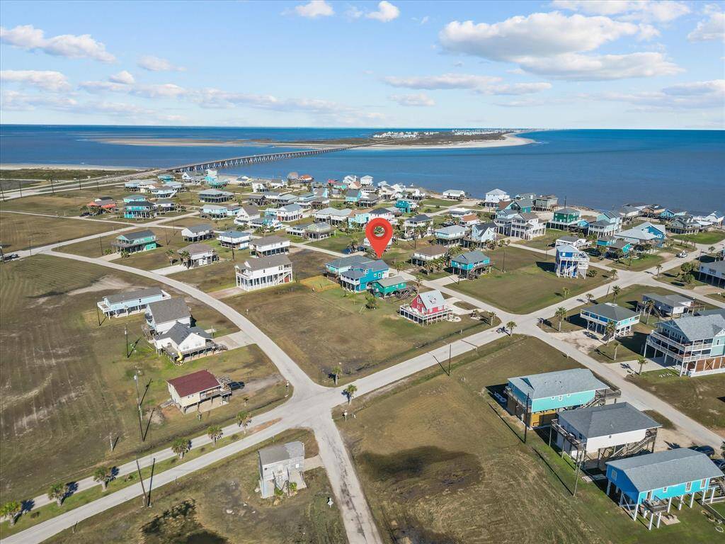 This aerial photo showcases a coastal community with charming beach houses, many elevated on stilts. The neighborhood is close to the shoreline, providing easy beach access and scenic ocean views. The area is tranquil, with spacious plots and a well-laid-out grid of streets, ideal for a serene lifestyle or vacation retreat.