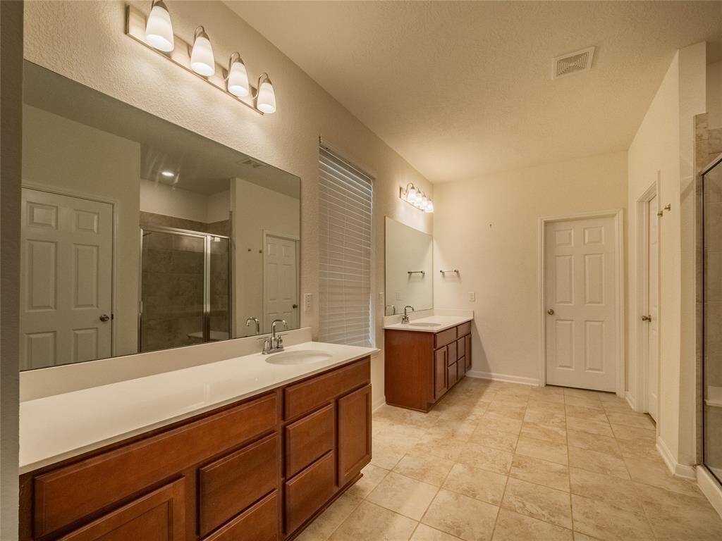 primary bathroom has double vanities both with oversized mirrors and plenty of storage